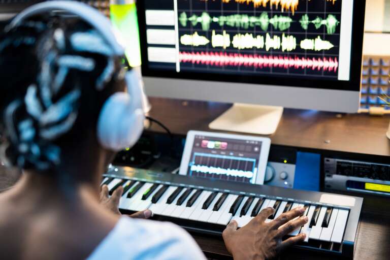 African or mixed-race young man touching keys of piano keyboard by computer