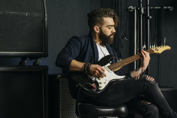 Bearded man playing guitar in a music studio